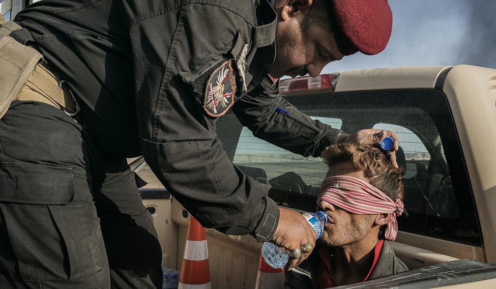 An Iraqi soldier gives water to a captured IS fighter. An Iraqi soldier gives water to a captured IS fighter.