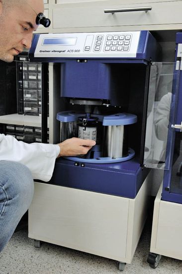 A watchmaker places a basket containing parts in the ultrasonic cleaning machine. A day at the Watch Spa