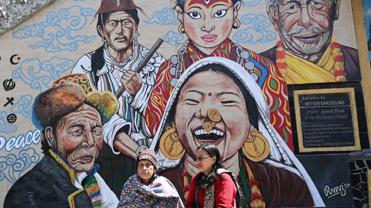 People stand under a large mural depicting the people of West Bengal's Darjeeling | Salil Bera