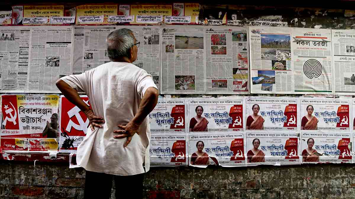 Future tense: An elderly man reads CPI(M) party newspaper pasted next to election posters in Kolkata | AP