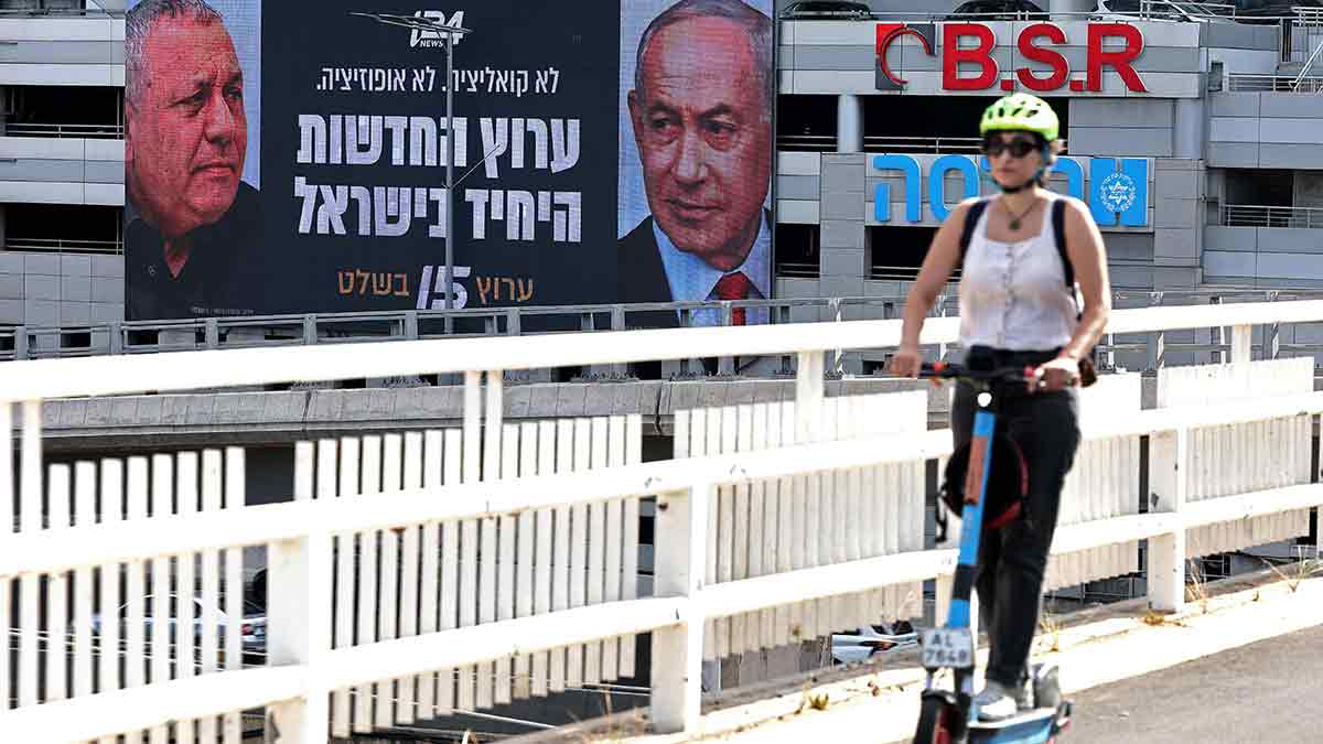 To bibi or not to bibi: A woman rides past an advertisement featuring Israel Prime Minister Benjamin Netanyahu (right) and Gadi Eisenkot, the leading opposition contender in the upcoming elections, along a street in Ramat Gan on September 23 | AFP