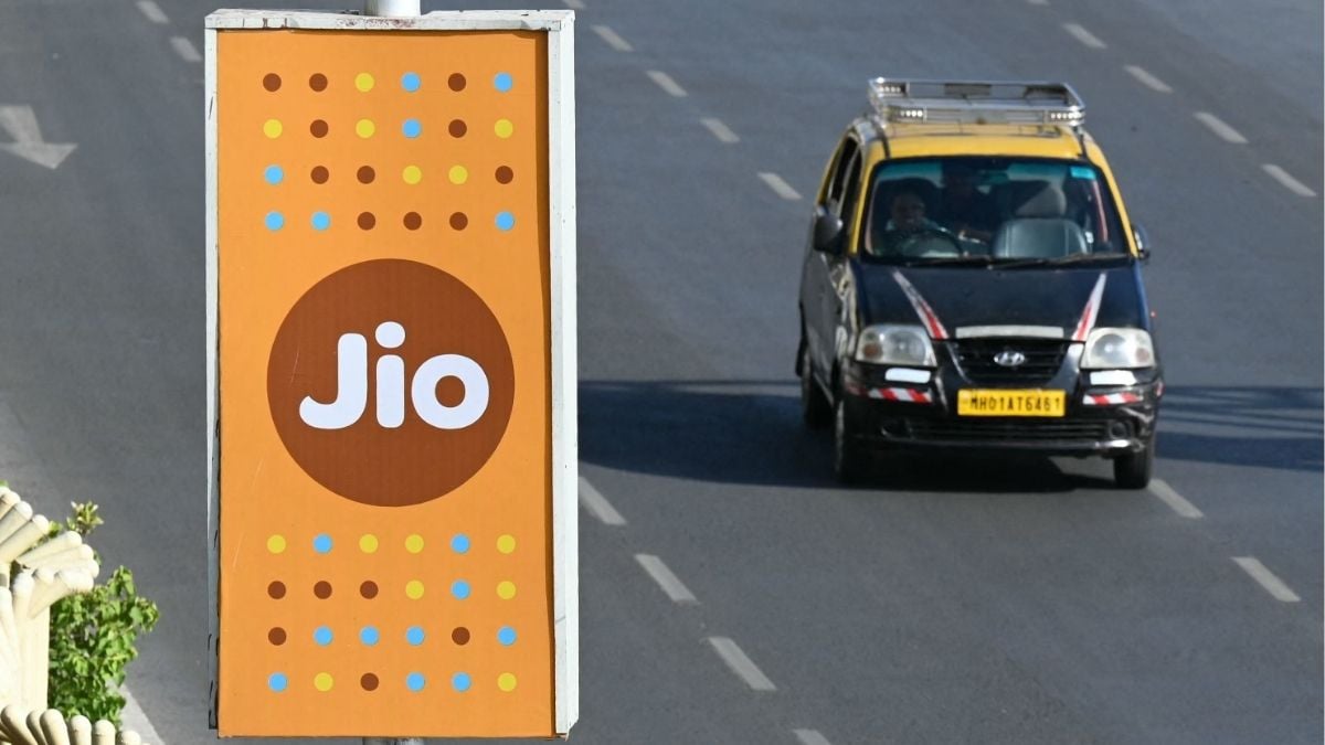 A taxi driver rides past a Jio advertisement in Mumbai on June 19, 2026 | AFP