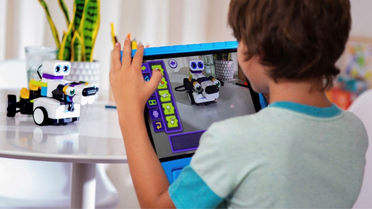 A kid uses an educational toy robot alongside his tablet | Botzees