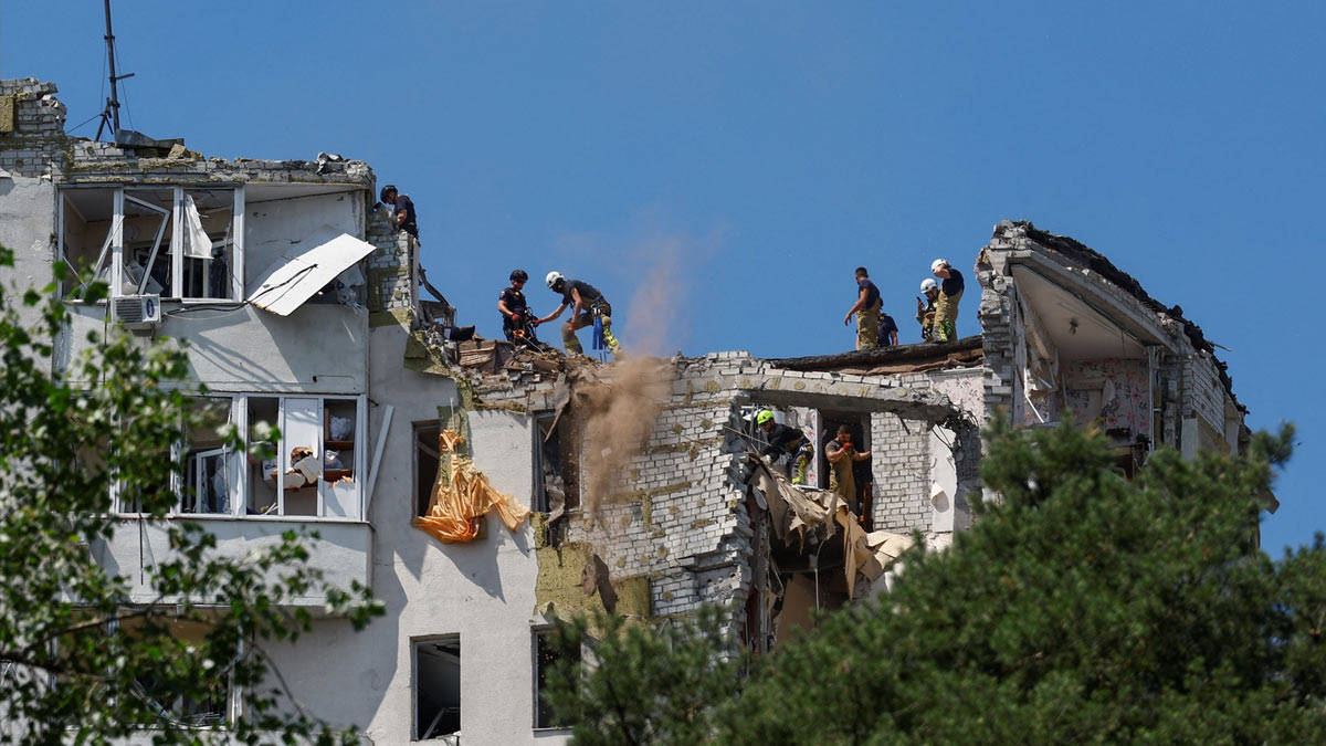 Rescuers work atop an apartment building damaged during overnight Russian missile and drone strikes in Kyiv