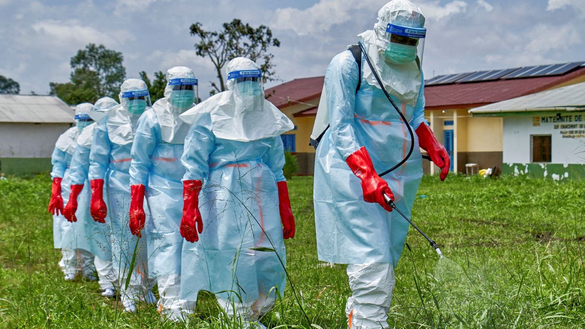 Red Cross workers walk in a formation as they disinfect Rwampara general hospital before handling the body of a person who died of Ebola | Reuters