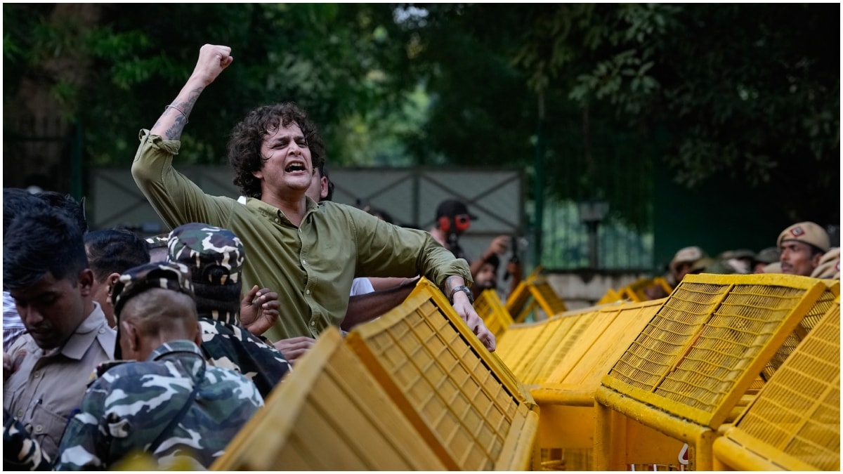 A protester shouts slogans as he climbs onto a police barricade during a march by opposition parties toward the Supreme Court demanding the resignation of Chief Election Commissioner Gyanesh Kumar in New Delh | AP