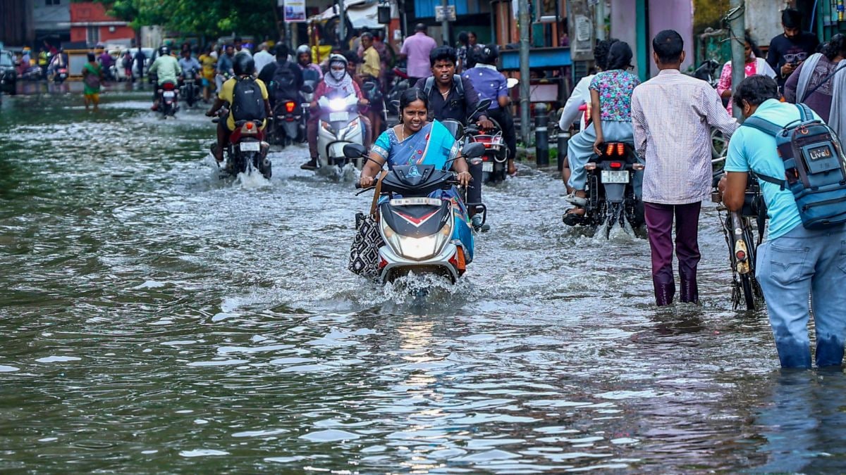 Commuters wade through a waterlogged street following heavy rain, in Chennai | PTI 