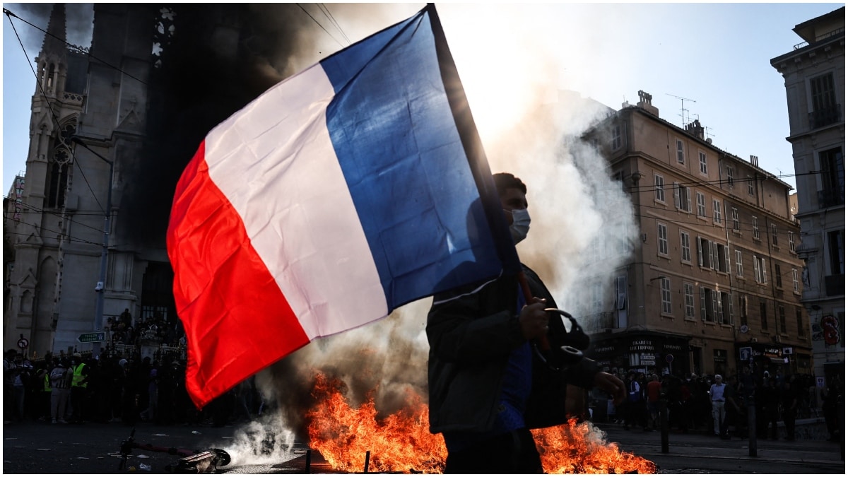 A protester waving a French national flag walks past a fire during clashes prior to the start of a demonstration to protest against the "high cost of living", in Marseille, southern France 
| AFP