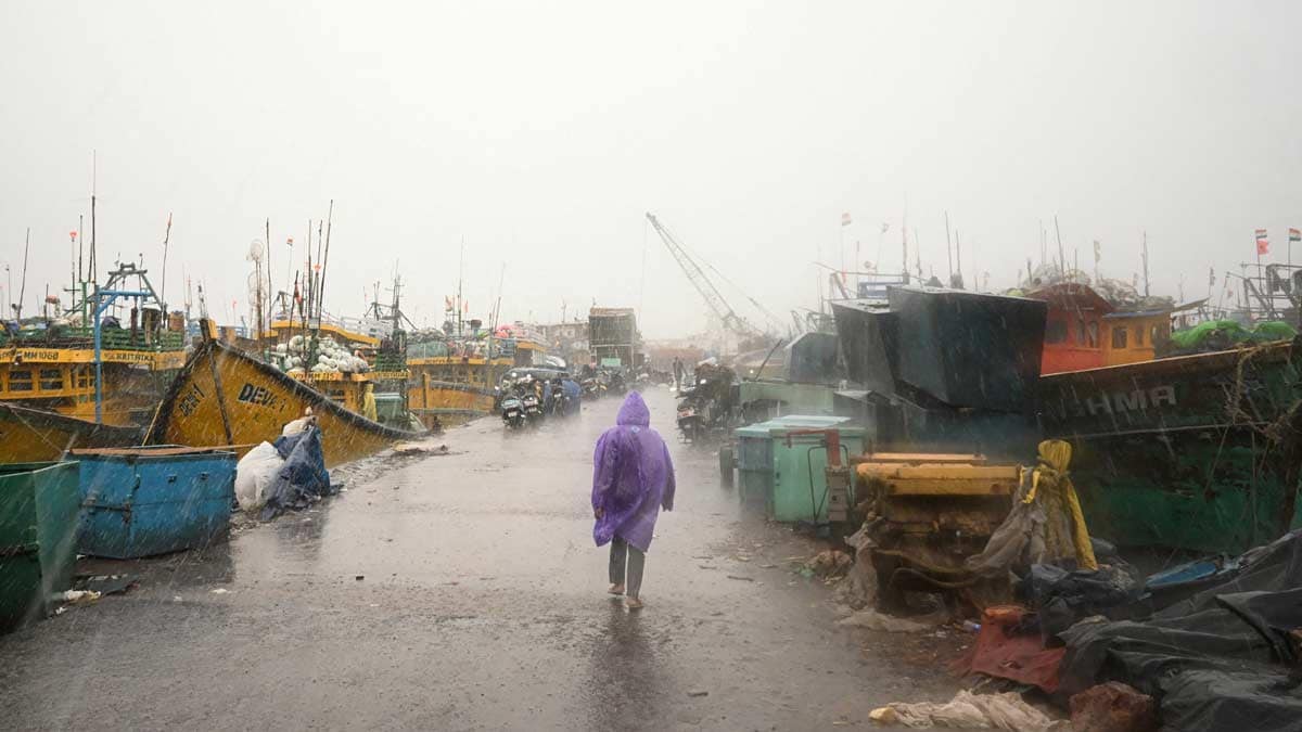 A man walks past docked boats along the harbour amid rain and gusty winds as Cyclone Arnab approaches, in Visakhapatnam | Reuters