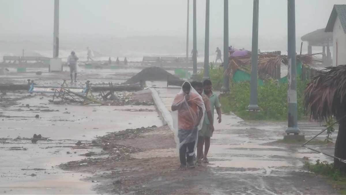  People walk amid strong winds and rainfall at a coastal area during Cyclone Arnab's landfall, in Kakinada | PTI