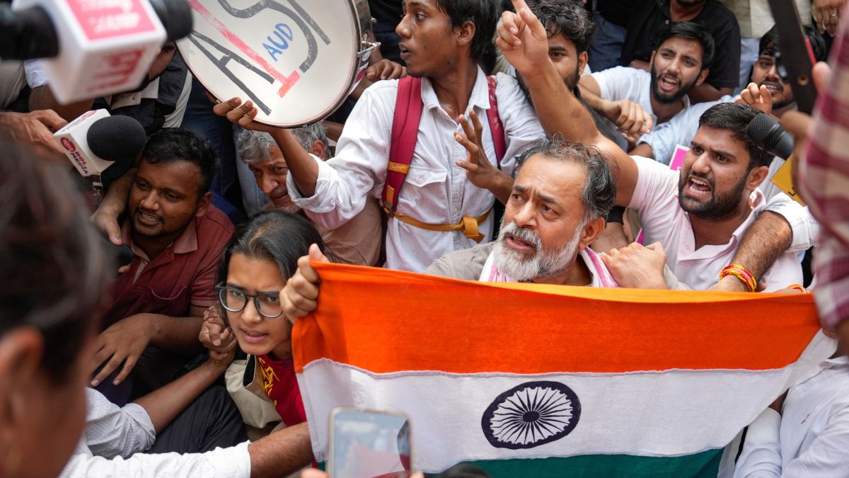 Activist Yogendra Yadav, AISA National President Neha Bora, and other student activists hold the national flag and raise slogans during a protest demanding the resignation of CEC Gyanesh Kumar at Jantar Mantar in New Delhi | PTI 