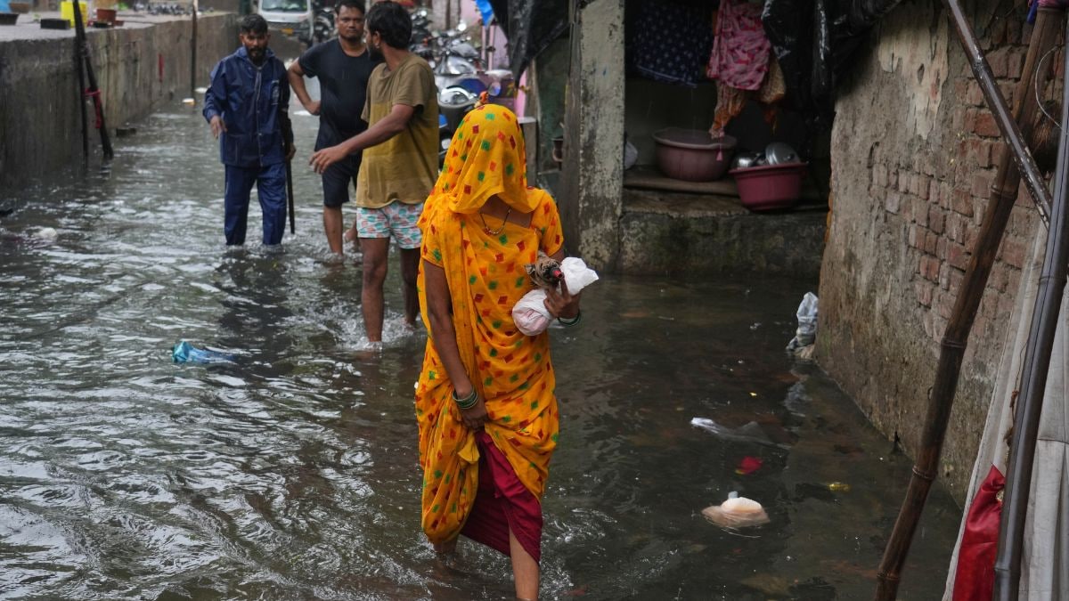 A woman walks through a waterlogged slum following monsoon rains in Mumbai | AP