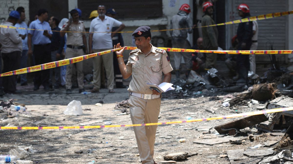 A police officer walks in between security tapes at the spot after a fire at a hotel in New Delhi | Reuters