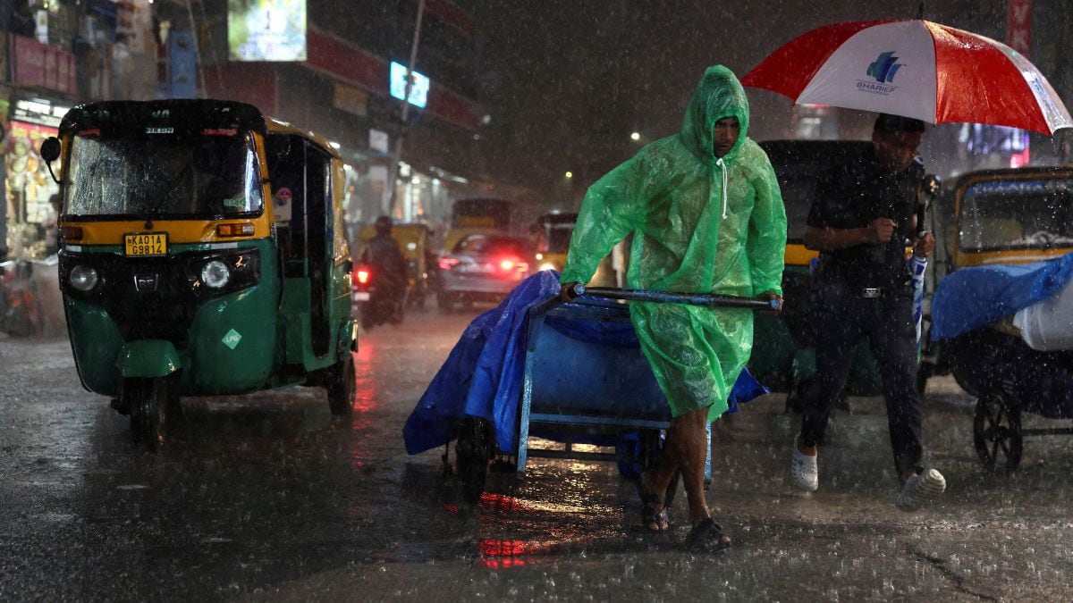 A man pulls a cart packed with goods during rain in Bengaluru, India | Reuters