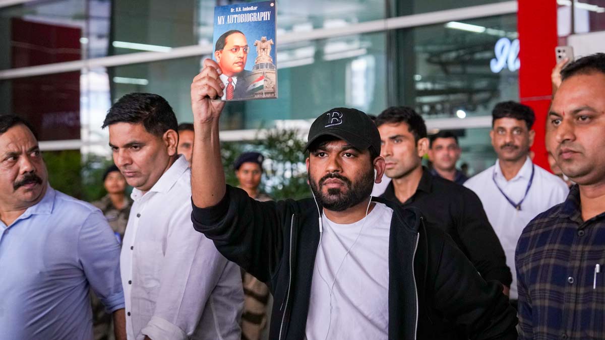 Cockroach Janta Party (CJP) founder Abhijeet Dipke, in black cap, holds a copy of autobiography of Dr. BR Ambedkar as he arrives at the Indira Gandhi International Airport, in New Delhi | PTI