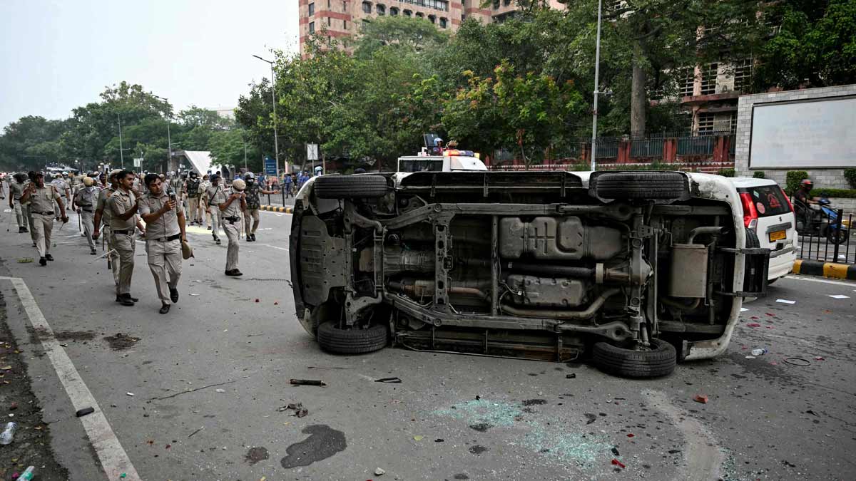 Police personnel take pictures of their damaged vehicle after they clash with Cockroach Janta Party  supporters | AFP
