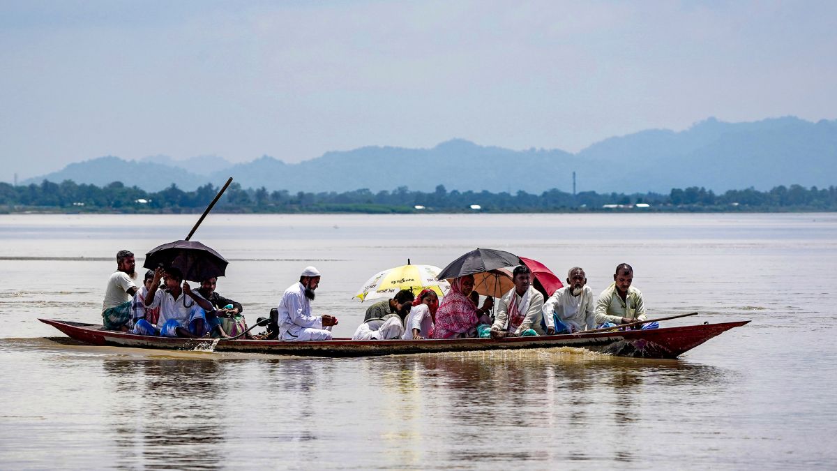 People cross the swollen Brahmaputra river while moving to a safer place following floods and incessant rain, at Khandahkhati Char in Morigaon, Assam | PTI