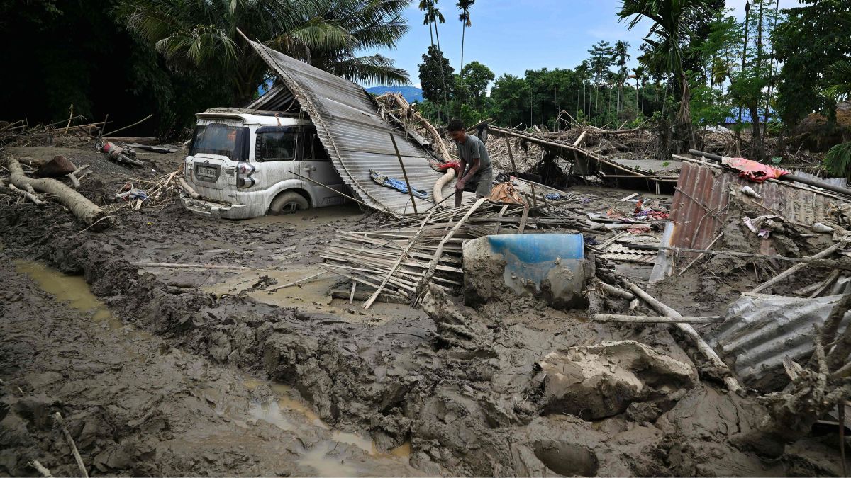 [File] A man searches for belongings amid the remains of his house, washed away by flash floods owing to heavy rain at a village in Assam's Sivasagar district on July 26, 2026 | AFP