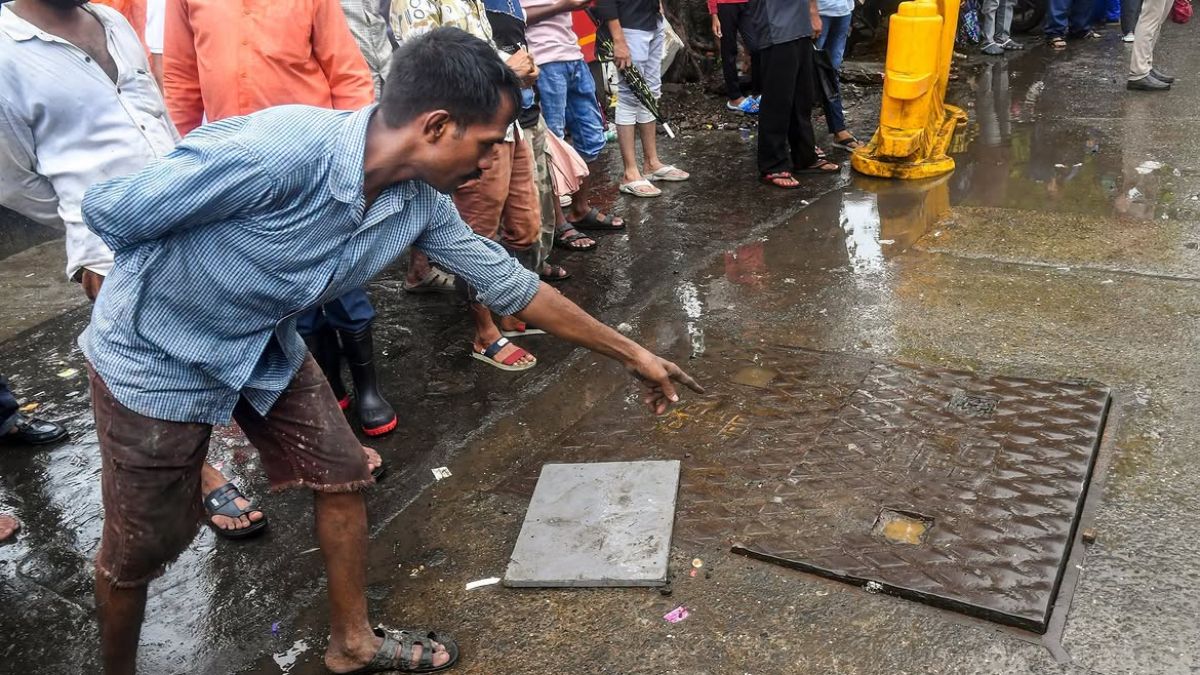 Representative image of a man pointing to a manhole cover in Mumbai | PTI