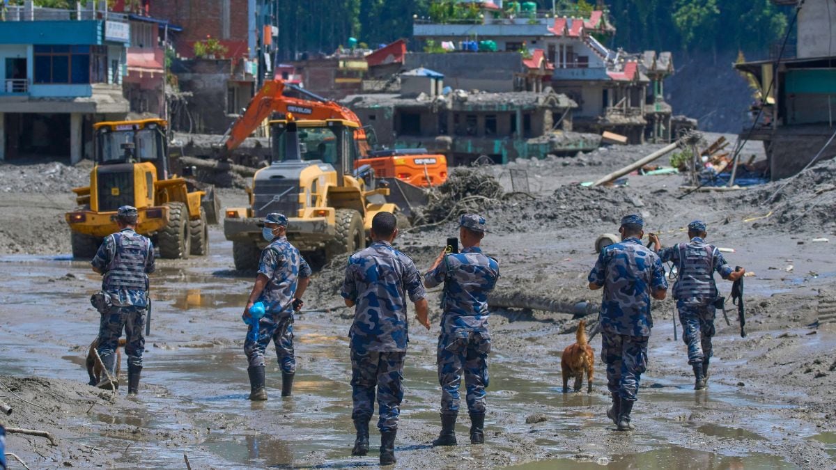 Nepalese policemen watch as earthmovers clear the debris of flash flooding in Nepal's Nuwakot district on August 27, 2026 | AP