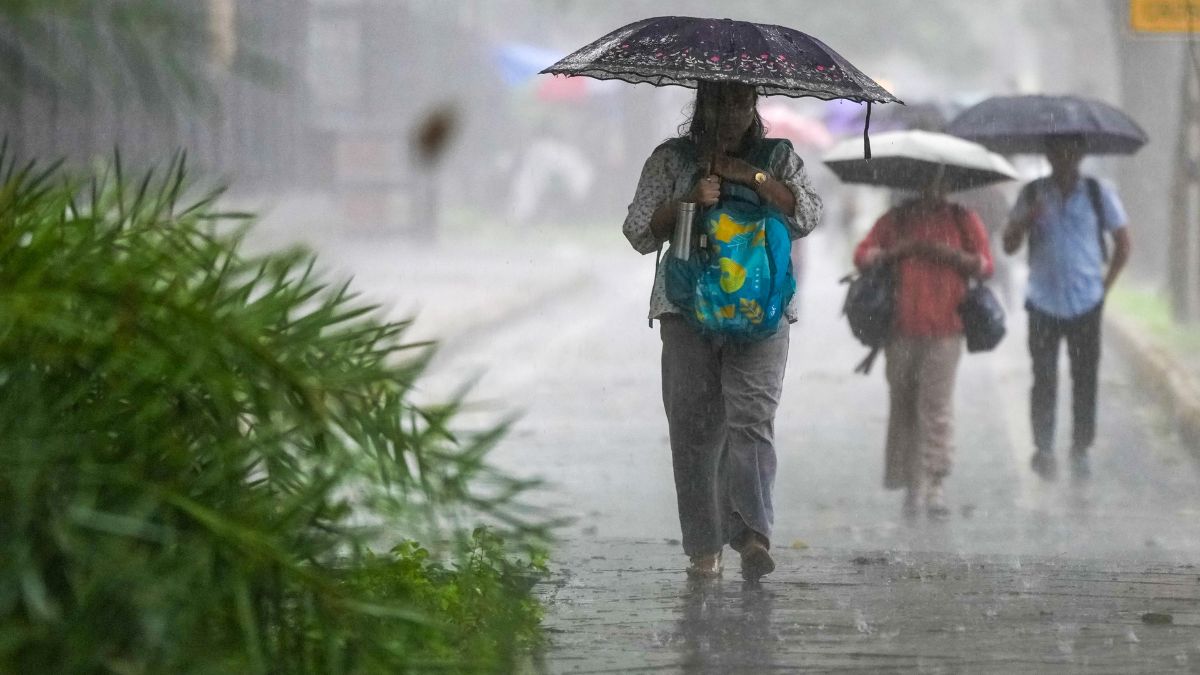 Commuters walk on a road amid heavy rain, in New Delhi, Thursday | PTI