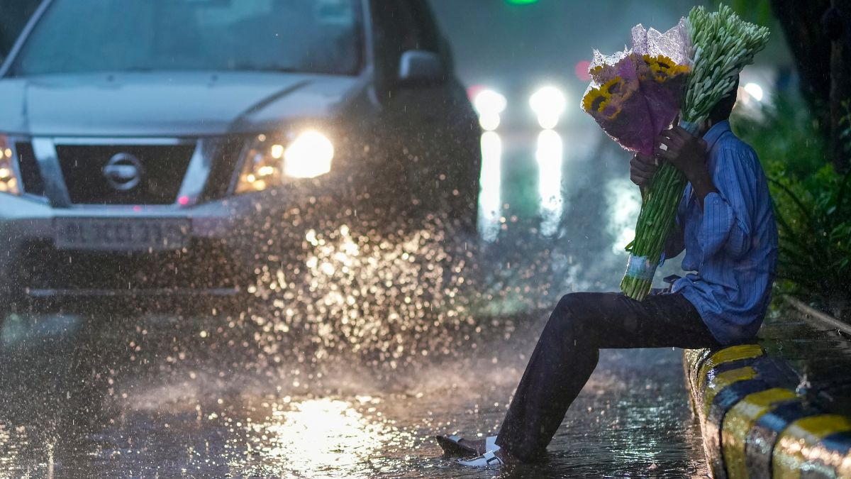 A roadside flower vendor sits on a platform amid rainfall, near Delhi High Court, in New Delhi, Friday, Aug. 7, 2026 | PTI