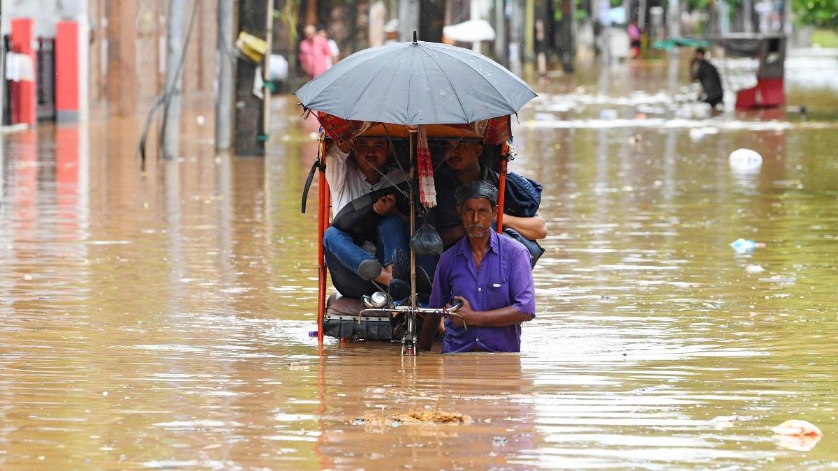 Commuters wade through a flooded road following heavy monsoon rainfall in Guwahati on September 1 | AFP
