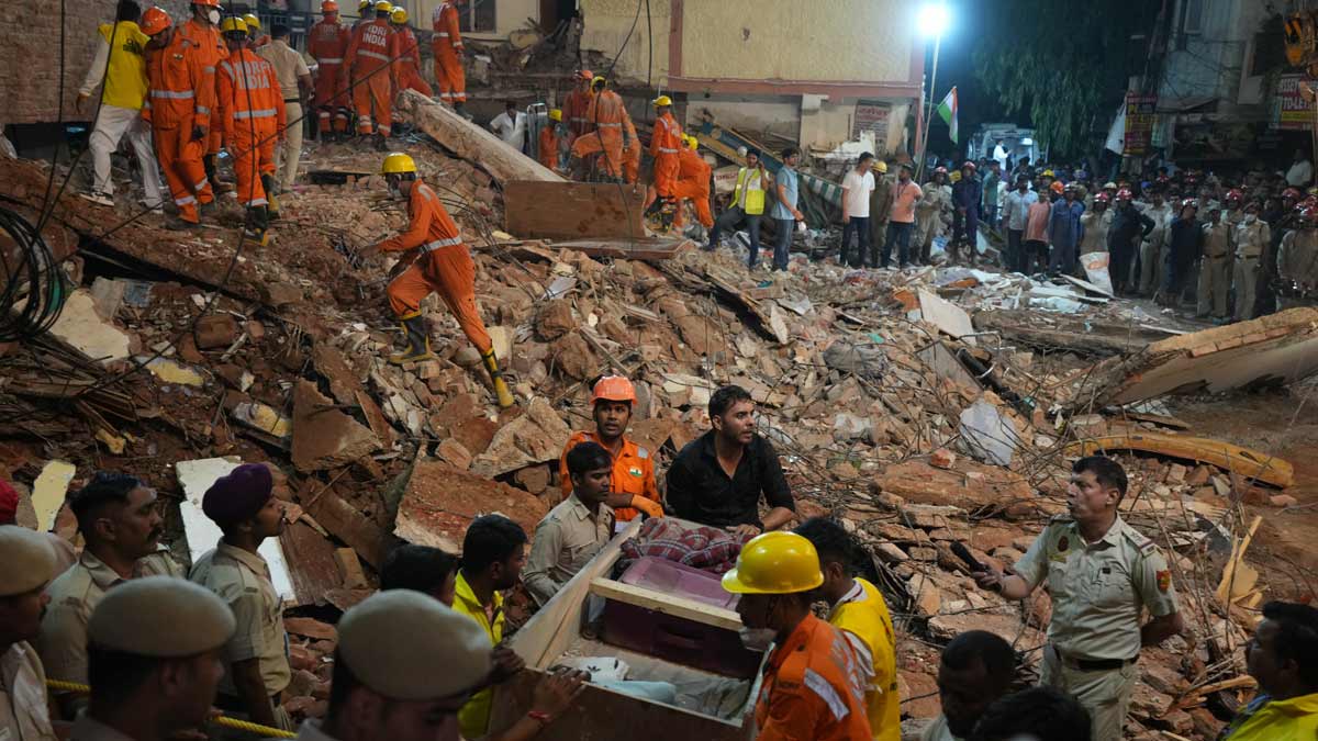 Rescue workers look for the trapped survivors under the debris of a building that collapsed in New Delhi | AP