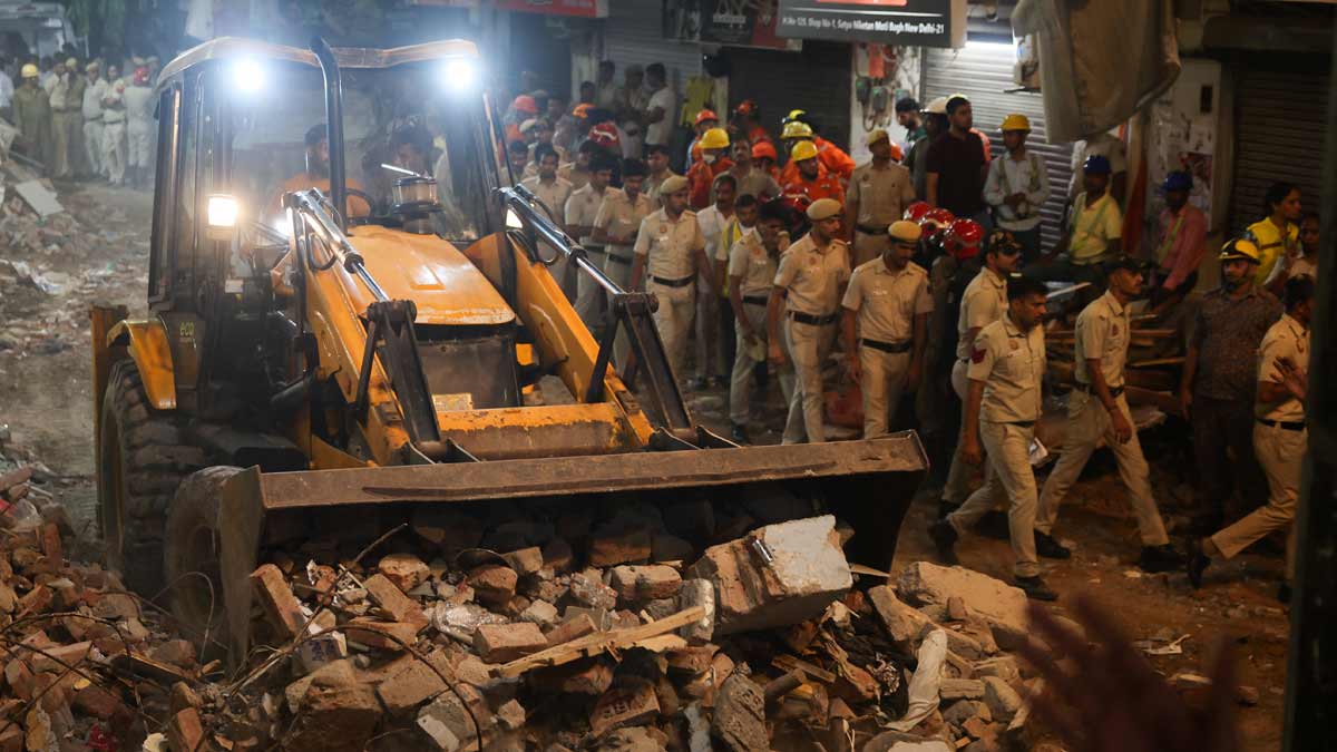Emergency personnel work at the site and look for survivors after a building collapsed, in New Delhi on Sunday | Reuters