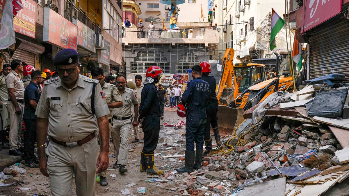 Rescue personnel stand near debris during a rescue operation on the second day after a 50-year-old five-storey building collapsed in South Delhi | PTI