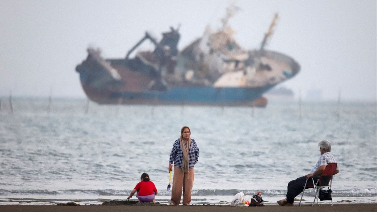 File photo for representation: People gather on a beach, as a vessel in the Strait of Hormuz is visible, near the beach of Bandar Abbas, Iran, May 31, 2026. | WANA via REUTERS