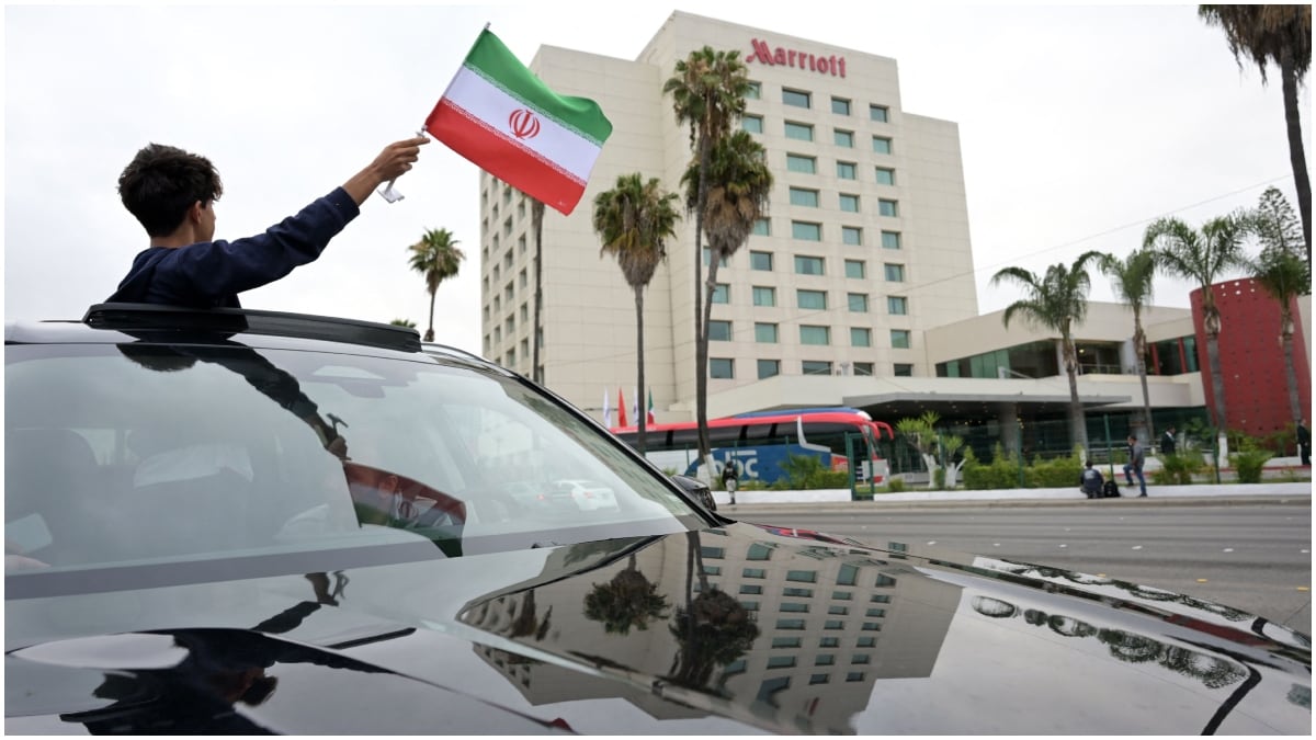 A young fan waves an Iranian flag from a vehicle outside the hotel where Iran's players are staying following their arrival in Tijuana, Mexico | AFP
