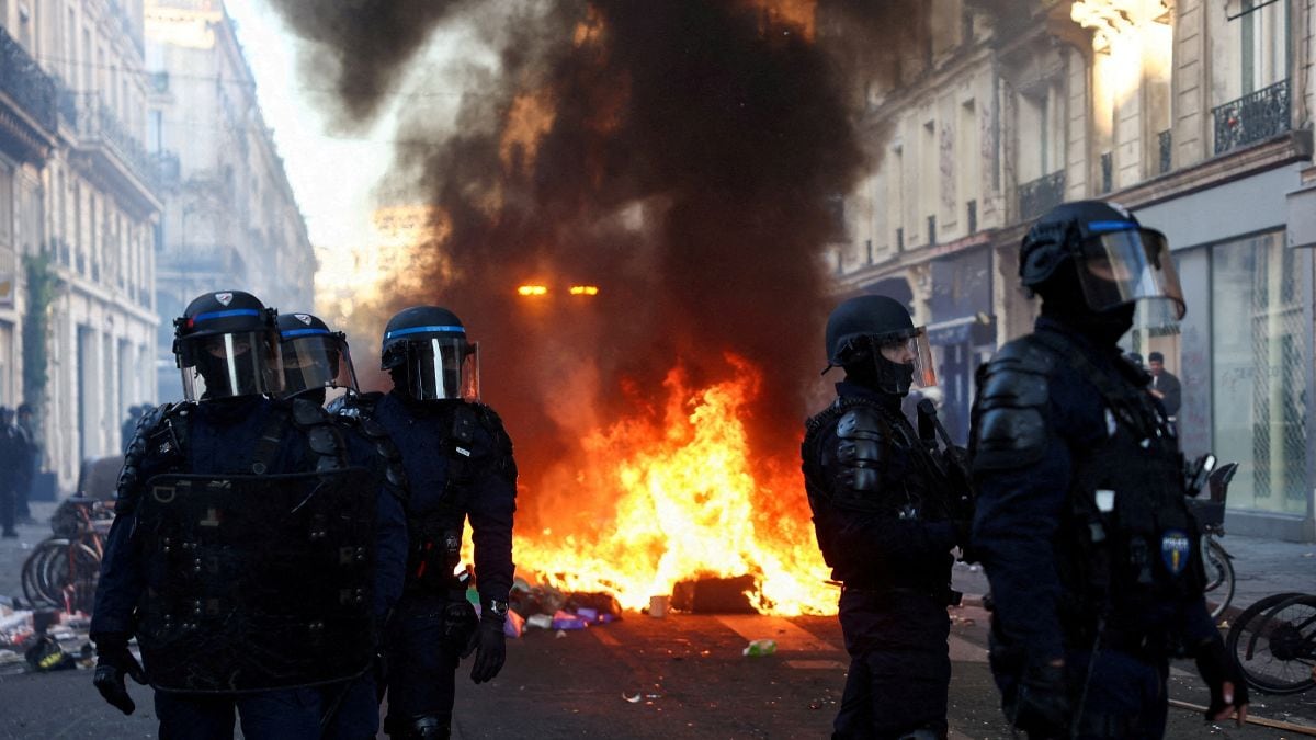  A fire burns, as Police officers in riot gear stand guard, during civil unrest, the day after a national day of demonstrations against the cost of living and rising fuel prices, in Paris | Reuters 