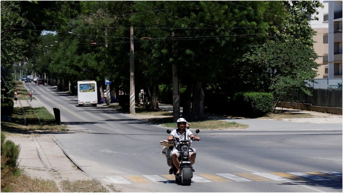 People ride a motorcycle along a street several days after local authorities declared a state of emergency amid the Russia-Ukraine conflict in the Black Sea resort city of Yevpatoriya, Crimea | Reuters 