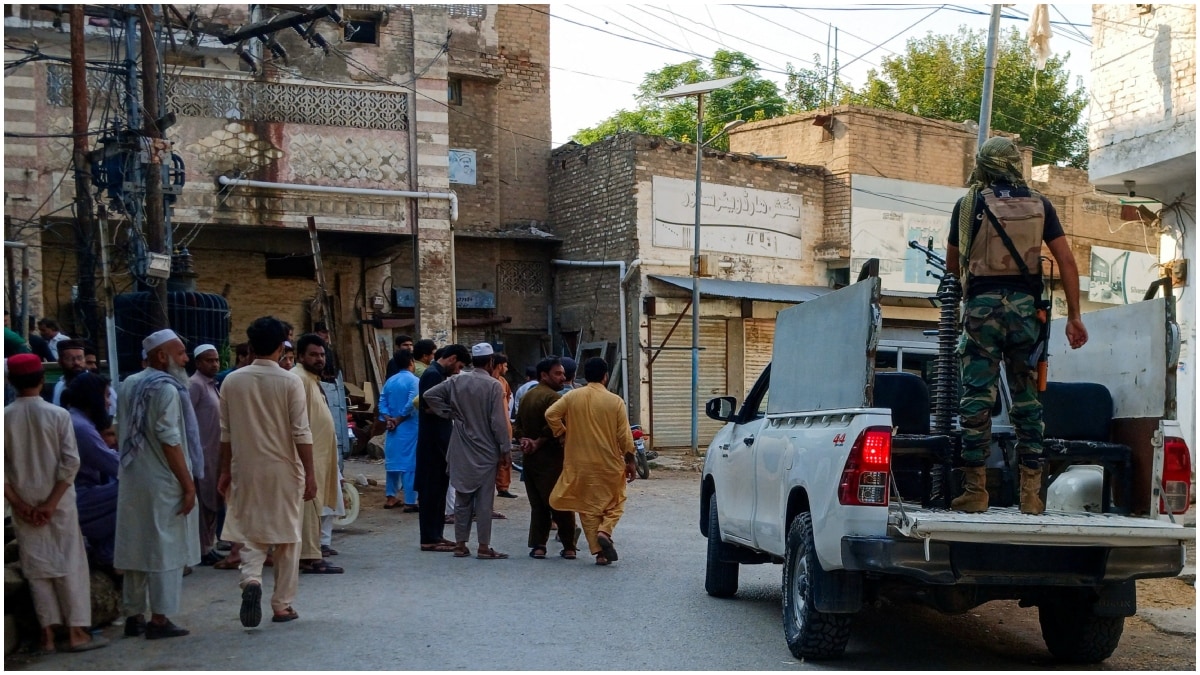 Residents and a police vehicle on a street following a suicide attack at a police facility in Kohat | Reuters