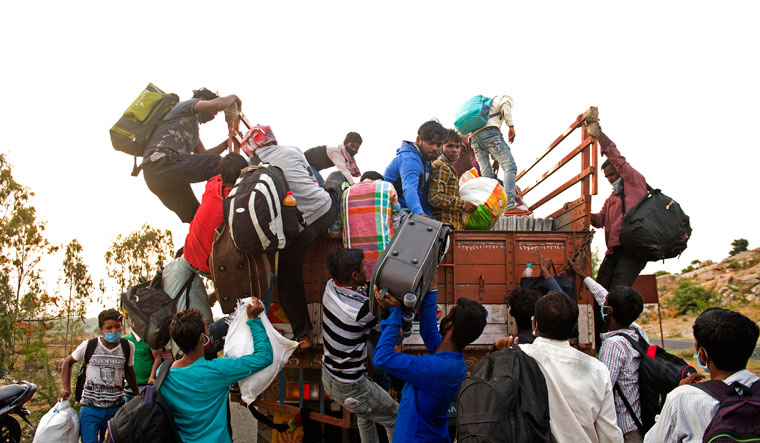Tales of survival: Migrants desparate to go home during the Covid-induced lockdown trying to board an overcrowded truck at the Karnataka-Andhra Pradesh border | Bhanu Prakash Chandra