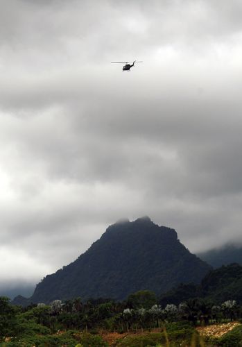 Taking stock: The helicopter belonging to the rescue team flies over the Doi Nang Non mountain range that houses the Tham Luang cave complex.