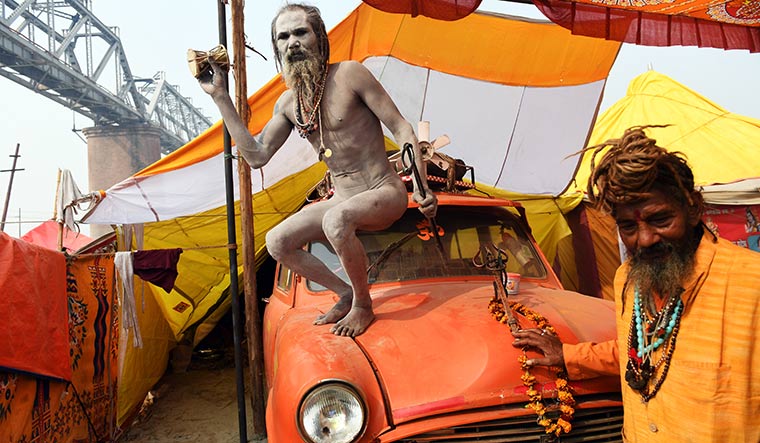 On beat: A naga sadhu plays damru, standing atop his saffron Ambassador under the railway bridge at the Kumbh.