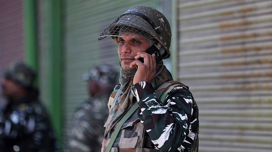 An Indian paramilitary soldier talks on his cellphone as he guards a closed market in Srinagar, Indian controlled Kashmir, Monday, Oct. 14, 2019.  Postpaid cellphone services were restored in India-administered Kashmir on Monday, more than two months after India's government downgraded the region's semi-autonomy and imposed a security and communications lockdown. (AP Photo/Mukhtar Khan)