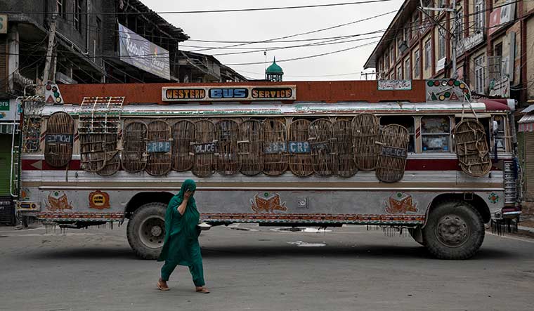 Road to nowhere: a woman walking past a bus-turned-barrier in srinagar on august 11 | Reuters