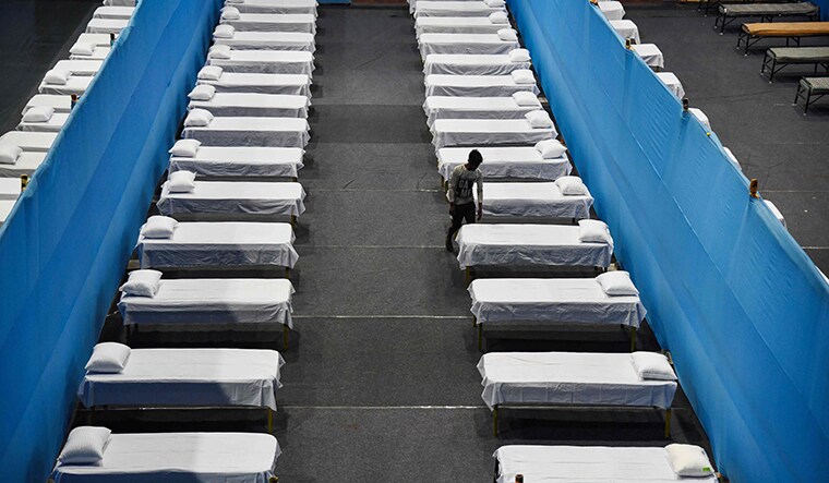 TOPSHOT - A worker arranges beds to prepare a quarantine centre in an indoor stadium at the Sarusajai Sports Complex during a government-imposed nationwide lockdown as a preventive measure against the COVID-19 coronavirus in Guwahati on March 29, 2020. (Photo by Biju BORO / AFP)