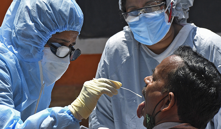 A BMC health worker collects swab sample of a passenger for COVID-19 test, at a station in Mumbai, Wednesday | PTI