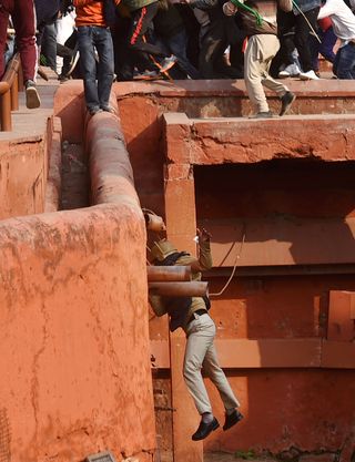 Failure to protect: A policeman falls from a rampart of the Red Fort during the clash with protesters | PTI