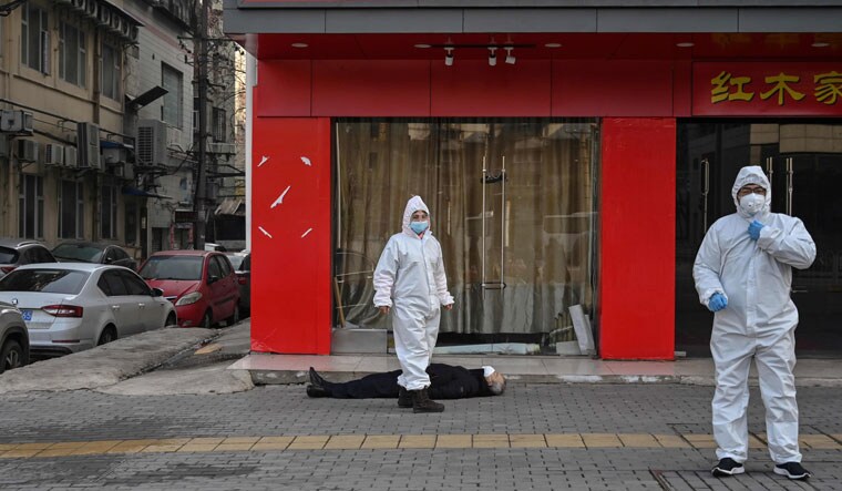 When it all began: A January 2020 photo of health workers checking on an elderly man who collapsed and died on a street in Wuhan, China | AFP
