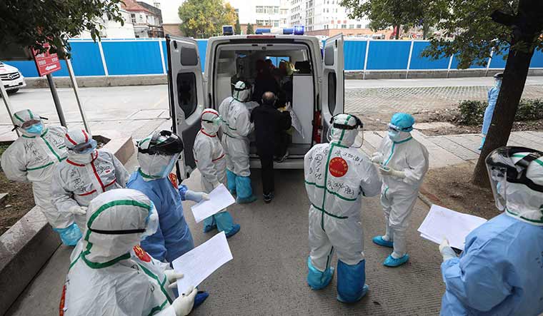 To the rescue: Medical staff assist a Covid-19 patient in Wuhan, China | AFP