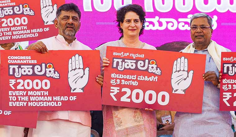 For her: Congress leader Priyanka Gandhi with Siddaramaiah (right) and D.K. Shivakumar during the release of the financial assistance scheme for women.