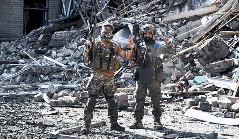Defending home away from home: Andrii (face covered) and Naveen at a school destroyed by a russian missile in Kostyantynivka near russia-occupied bakhmut. They said that they were proud indians but wanted to fight for ukraine as it was their home now.