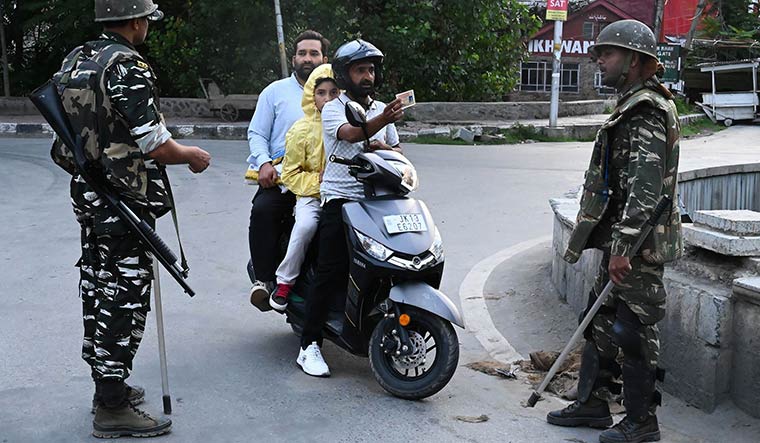 Uncertain road: A rider showing his ID card to security personnel in Srinagar on August 12 | AFP