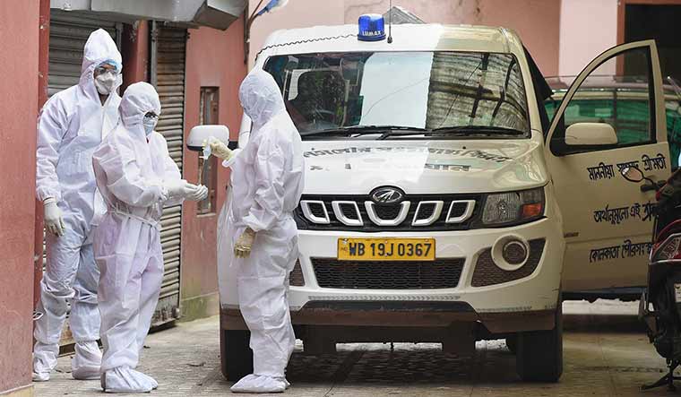 Breaking the chain: Kolkata Municipal Corporation workers sanitise their hands after putting the body of a dead Covid-19 patient in a vehicle | PTI