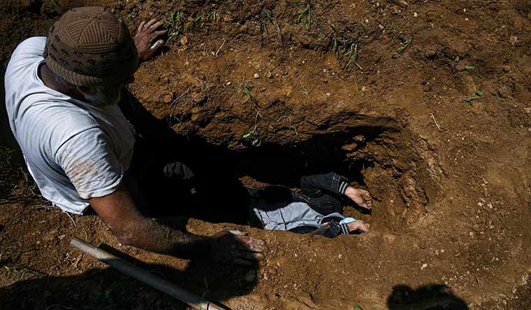 Immeasurable loss: Umar Farooq of Srinagar   measures a grave dug for his mother, who died of Covid-19 | AFP